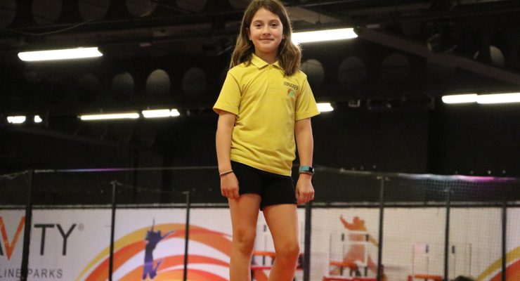 A girl on a trampoline smiles into camera