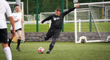 man in black football kit kicking ball