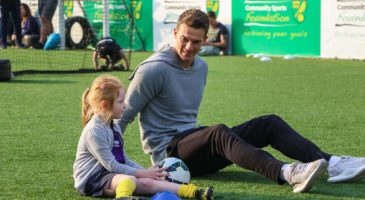 Young girl player sat on the ground with a football player