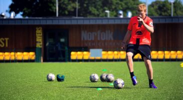 Boy in orange dribbling football