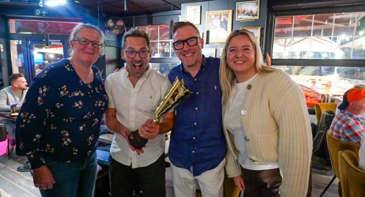 group of four people one holding a trophy