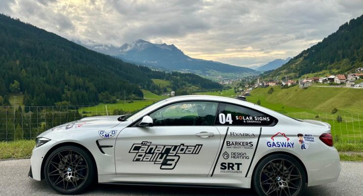 Car with signage in front of mountain landscape