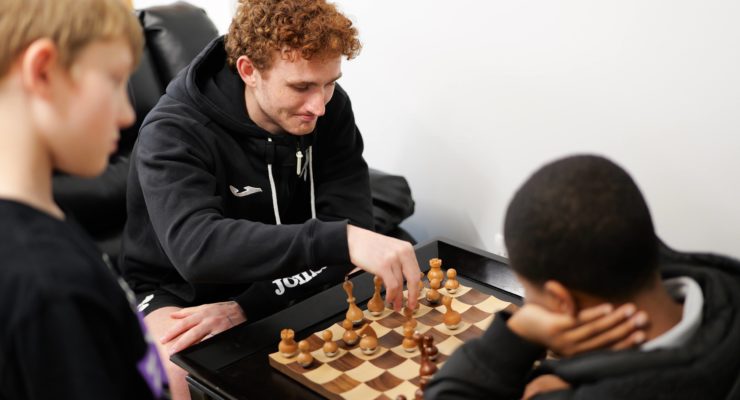 Josh Sargent plays chess with young participant