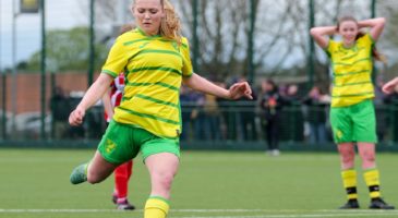 Girl in Norwich kit kicking a football