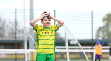 Boy in Norwich kit with hands on his head