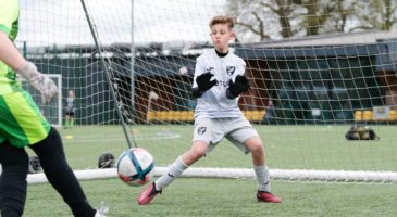 Goalkeeper wearing Norwich kit prepares to make a save