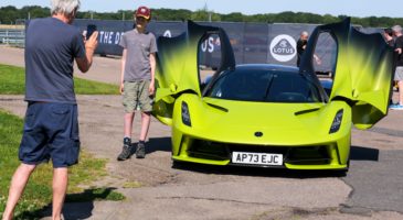 a boy standing next to a green car with the doors open