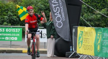 a rider in a red top crossing the finish line