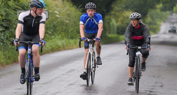 Three riders cycling on road