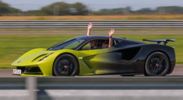 lotus car going around the track with people waving from inside