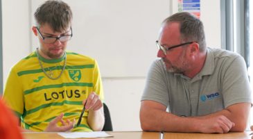 a boy in a yellow stop sitting next to a man in a grey top