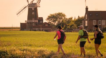 three people walking with a windmill in the background