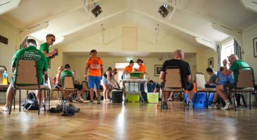 inside a village hall with people sitting and standing