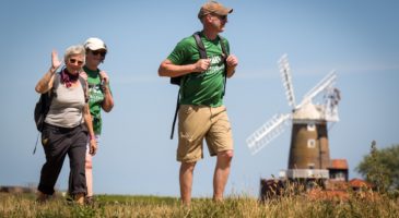 three people walking with windmill in the background
