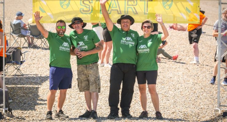 group of four people in green tshirt standing under start banner