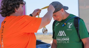 woman in orange top offering medal to man in green top