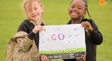 two girls holding a sign that says 'go'