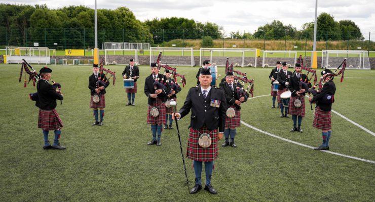 bag pipe band standing on football pitch