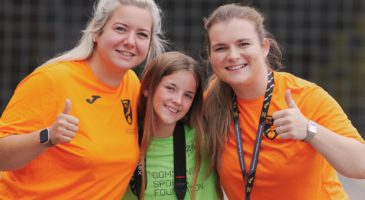 two women in orange tops and a young girl in a green top