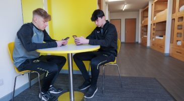 two boys sitting at a table in a bunkbox