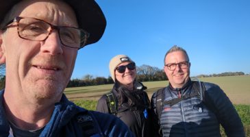 man taking selfie with two people in the background