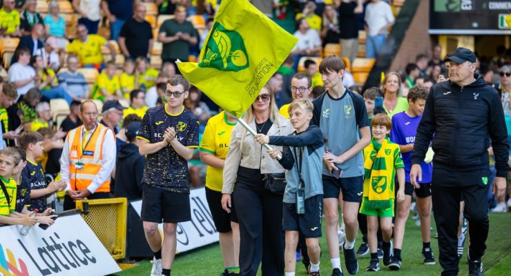 Group of people walking around a pitch with a large flag