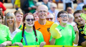 Group of people smiling in green and orange tshirts