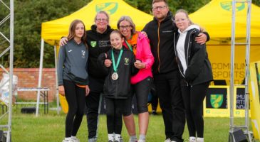 a group of people with a child wearing a medal