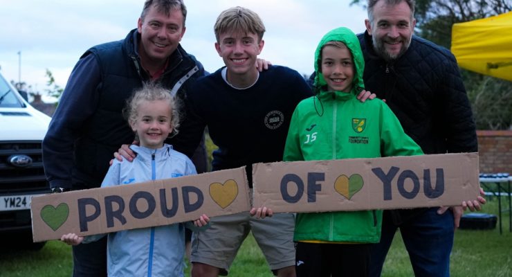 a group of people holding a sign saying proud of you