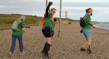 three women walking on stones waving