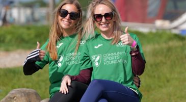 two women in green tops giving thumbs up