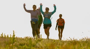 three women walking, two with their hands in the air