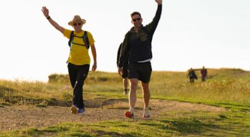 two men walking waving a hand in the air