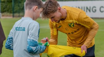 norwich city players signing a shirt for a boy