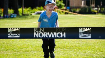 child running towards a run norwich banner