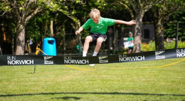 child running towards a run norwich banner