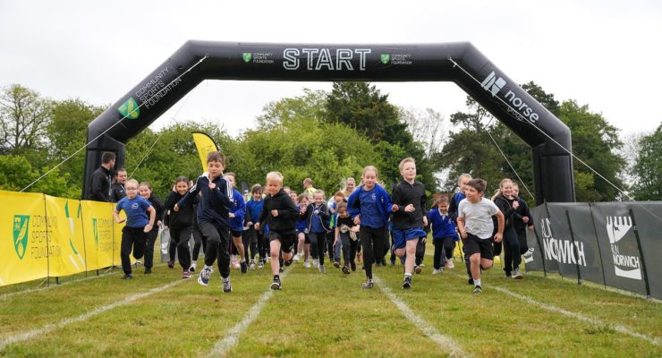group of children running underneath an inflatable gantry saying start