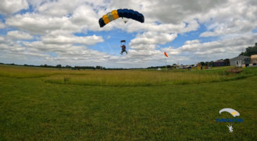 skydiver about to land on grass with parachute open