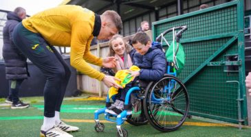 norwich city player signing a short for a boy in a wheelchair