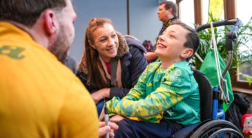 a boy in a wheelchair smiling with a woman beside him