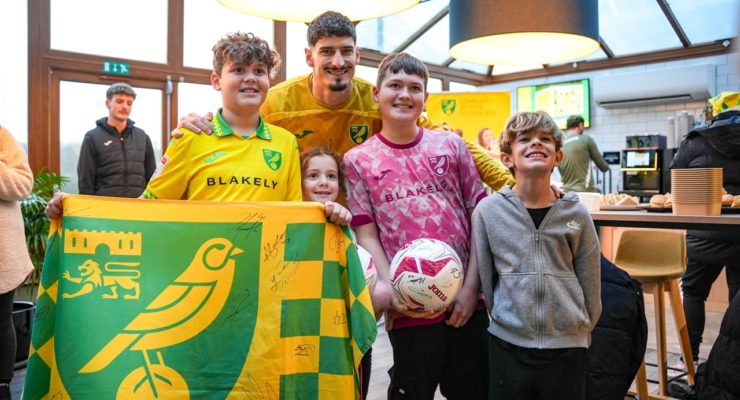 group of norwich city fans with signed flag