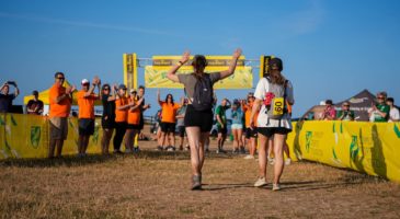 two people walking towards a finish line with a group of people cheering them on