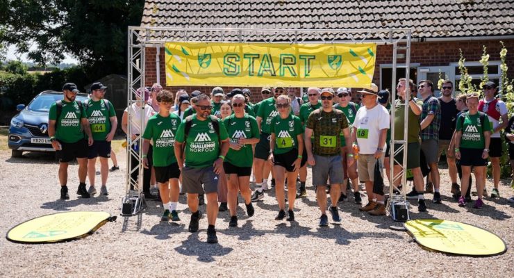 Group of walkers in green tshirts walking under a banner that says start