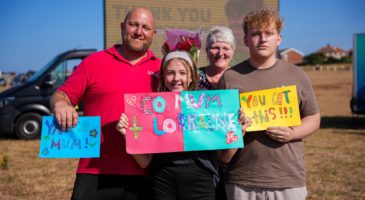 three adults and a child holding signs of support