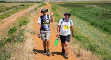two men walking with sunhats on
