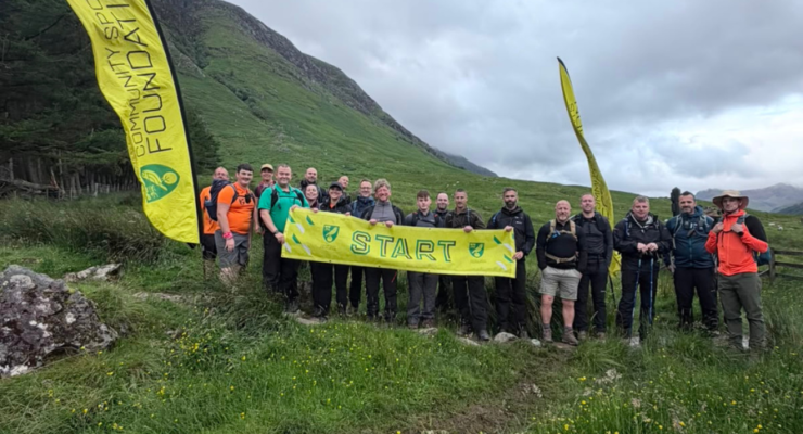 group of people standing at the base of Ben Nevis holding a banner that says start